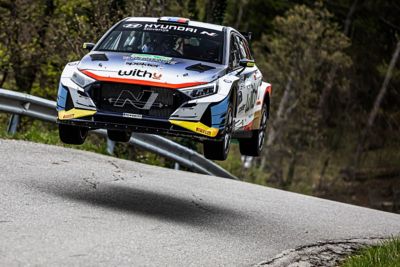 Hyundai i20 N Rally2 racing on track getting some air.