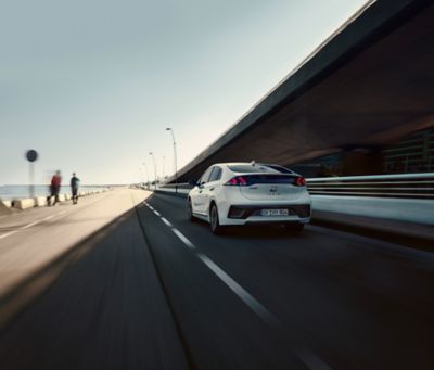 Hyundai IONIQ driving on a road next to the shore.