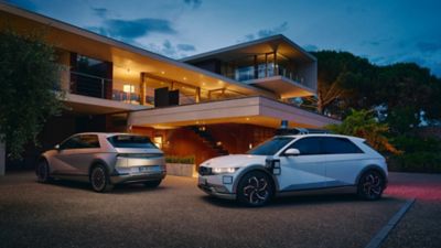 Hyundai IONIQ 5 and Robotaxi in the driveway of a modern house.
