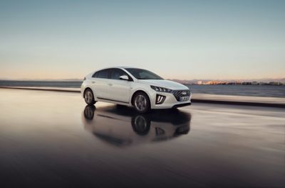 The Hyundai IONIQ Plug-in Hybrid driving on a wet road during a sunset.