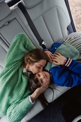 Eine Mutter küsst Ihren Sohn auf dem Rücksitz eines Hyundai Elektrofahrzeugs.