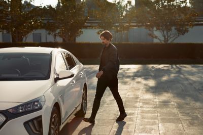 Muž přicházející k zaparkovanému novému Hyundai IONIQ Electric.