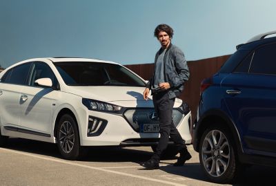 The new Hyundai Kona in Surfy Blue from the side driving over a bridge.