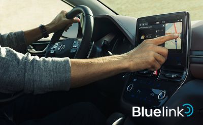 Muž v sedadle řidiče ovládající dotykovou obrazovku nového vozu Hyundai Ioniq Plug-in