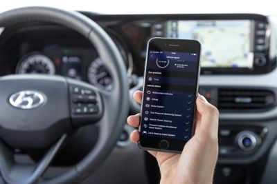 Kierowca Hyundaia i10 Nowej Generacji trzymający w dłoni smartfona, korzystający z aplikacji Bluelink