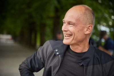 A portrait of Bertrand Piccard wearing a dark shirt and jacket. 