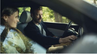 Looking inside a Hyundai through the passenger window, a couple inside looking at the touchscreen.