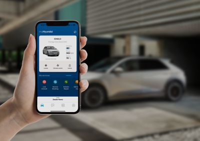 A hand holding a mobile phone showing the IONIQ 5 on the Bluelink app.
