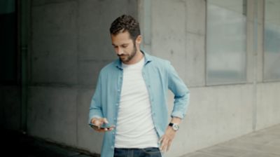 Homme marchant sur le trottoir et regardant son téléphone.