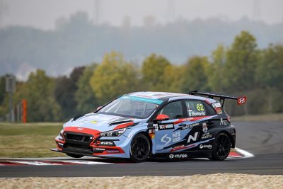 The Hyundai Motorsport’s i30 VELOSTER N TCR in action on a racetrack shown from the side.