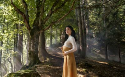Una foto di una donna incinta in una foresta mentre tiene il pancione