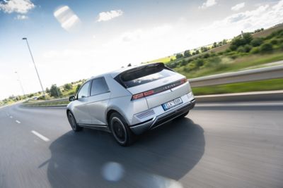 IONIQ 5 jedoucí po moderní cestě v krásném letním počasí.