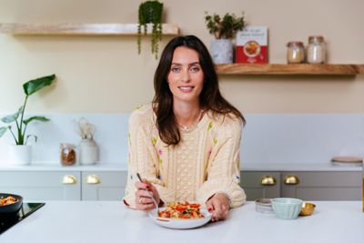 Ella Mills leaning on a kitchen counter with a Hyundai plant-based Challenge meal.