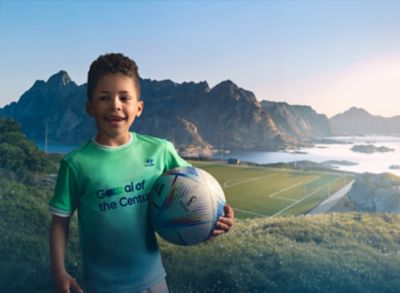 Mladý chlapec v dresu Hyundai Goal of the Century drží fotbalový míč.