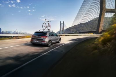 The Hyundai i30 bike carrier driving on a road towards a bridge.