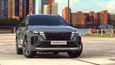 Frontview of the Hyundai TUCSON Plug-in Hybrid N Line in shadow gray in front of a skyline.