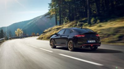 Hyundai i30 Fastback N Drive-N Limited Edition in Phantom Black Pearl driving on a curvy road.