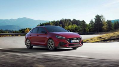 The new Hyundai i30 N racing a corner in the colour Sunset Red.