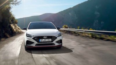 The Hyundai i30 N driving in a hilly set in the colour Polar White.