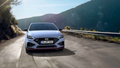 The Hyundai i30 N from the front in Performance Blue colour driving on a mountain road