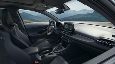 Blick in das Interieur eines Hyundai i30 Fastback N mit Lenkrad, Displays und Bedienelementen.