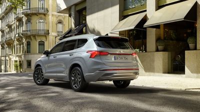 El nuevo Hyundai SANTA FE Híbrido Enchufable de 7 plazas visto desde detrás circulando por la ciudad.
