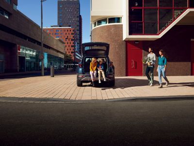Two kids sitting in the opened trunk of the Hyundai Tucson Hybrid compact SUV.