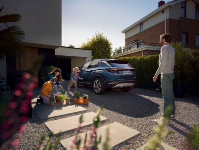 Eine Familie sortiert gekaufte Pflanzen in der Hofeinfahrt neben Ihrem geparkten Hyundai TUCSON.