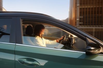 Woman in the drivers seat of the Hyundai BAYON compact crossover SUV with panorama roof.