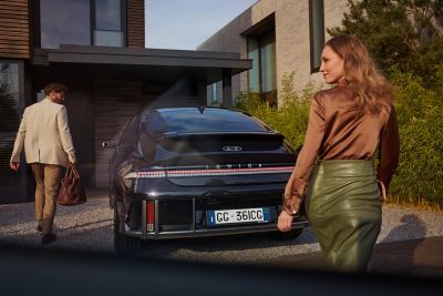Hyundai IONIQ 6 berlina coupé 100% elettrica parcheggiata con un uomo e una donna all'esterno