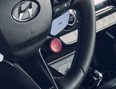 Detail of the red N Grin Shift button on the steering wheel of the Hyundai KONA N.