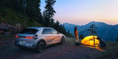 Hyundai IONIQ 5 V2L con donna e uomo accanto ad una tenda da campeggio
