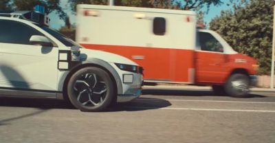 Hyundai IONIQ 5-based Robotaxi che si ferma sul ciglio della strada per un'ambulanza