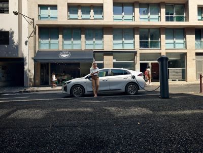 Afbeelding van een vrouw bij een Hyundai Ioniq die aan het opladen is.