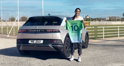 Nadia Nadim, miembro del Hyundai Team Century, sostiene su camiseta junto al IONIQ 5.