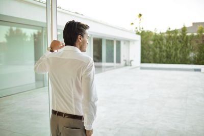 Person in button up shirt standing at a window, looking in the far.