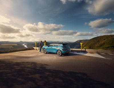 The new Hyundai Kona Electric standing in a parking lot with a great view over the country side.