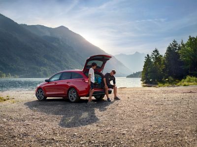 Mężczyzna z synem stoją przy samochodzie Hyundai z otwartym bagażnikiem. 