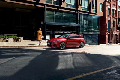 The new i30 N Line Hatchback parking on a street next to a glass front.