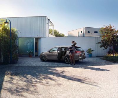 Un homme se tient debout avec un enfant dans les bras devant la Hyundai i30 Wagon.