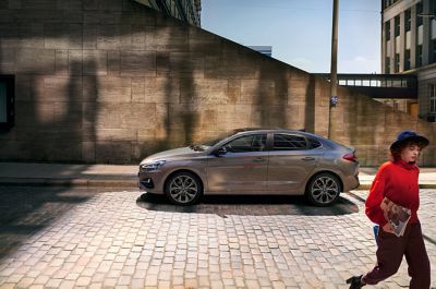 Young woman walking away from her parked Hyundai i30 Fastback