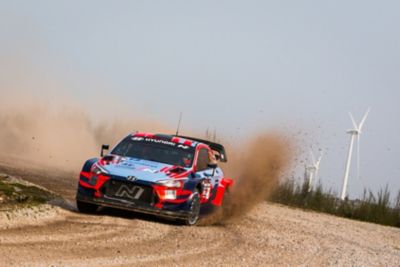 Hyundai i20 WRC na rajdzie jadący po piachu i szutrze. 
