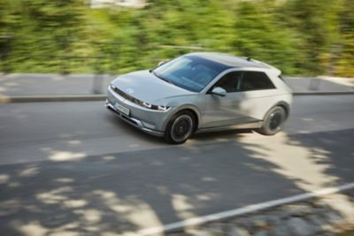 The Hyundai KONA Electric pictured from the front driving down a country road.