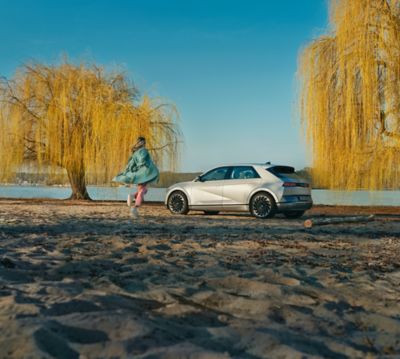 A person on a beach, approaching their Hyundai IONIQ 5 electric midsize CUV.