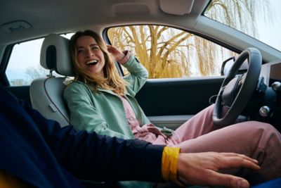 A happy woman on the passenger seat of a Hyundai full-electric vehicle.