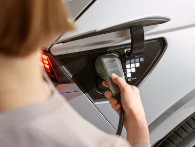 A young couple hanging out next to their Hyundai IONIQ 5 electric midsize CUV while it is charging.