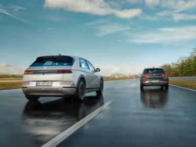 A Hyundai IONIQ 5 electric midsize CUV passing another car on a country road.