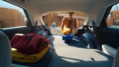 Muž nakladajúci do batožinového priestoru svojho automobilu Hyundai IONIQ 5 so sklopenými zadnými operadlami.