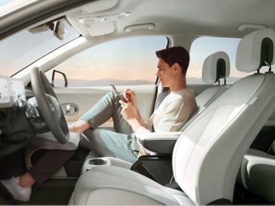 A woman resting in the reclined passenger seat insider her Hyundai IONIQ 5 electric CUV.