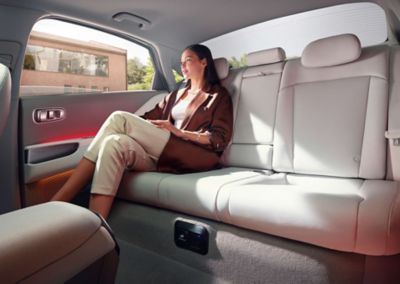 Una donna seduta sui sedili posteriori di colore grigio chiaro di Hyundai IONIQ 6 100% elettrica